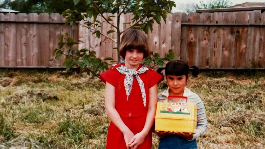 Jonelle Matthews holding a yellow basket next to a little girl wearing a red dress and a scarf