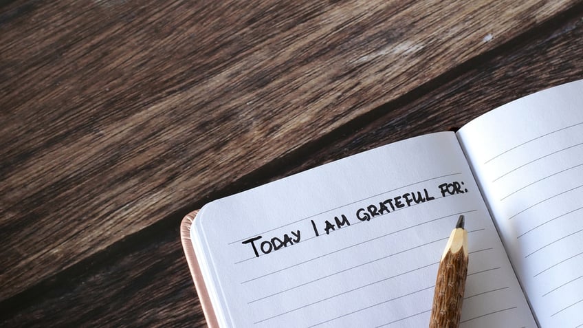 Open journal with handwritten text that reads "today I am grateful for"