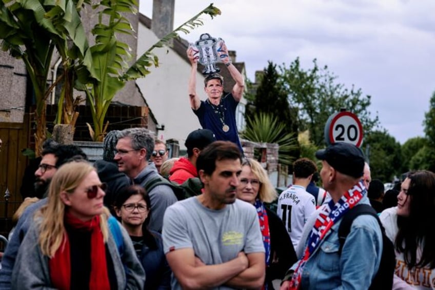 Crystal Palace supporters near Selhurst Park celebrate around a cardboard depicting manage