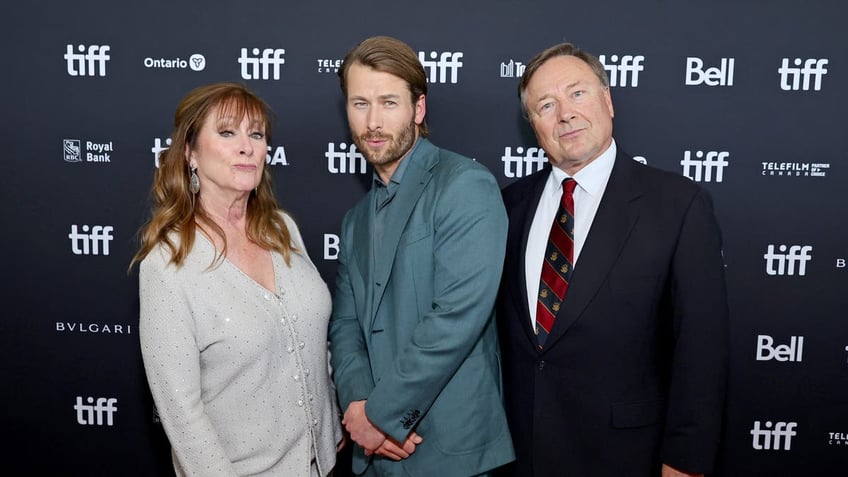 glen powell posing with his parents on the red carpet