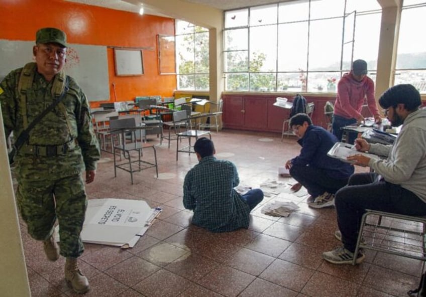 Electoral workers examine ballots while counting votes at a polling station in Cuenca, Ecu