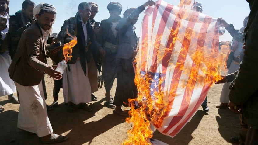 Houthi followers burn the Israeli and American flags during a tribal gathering on January 14, 2024 on the outskirts of Sana'a, Yemen. Houthi followers gathered to protest against the U.S.-U.K. airstrikes on positions in areas under their control. 