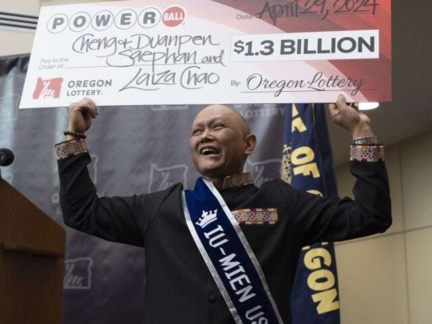 Cheng "Charlie" Saephan holds a display check above his head after speaking duri