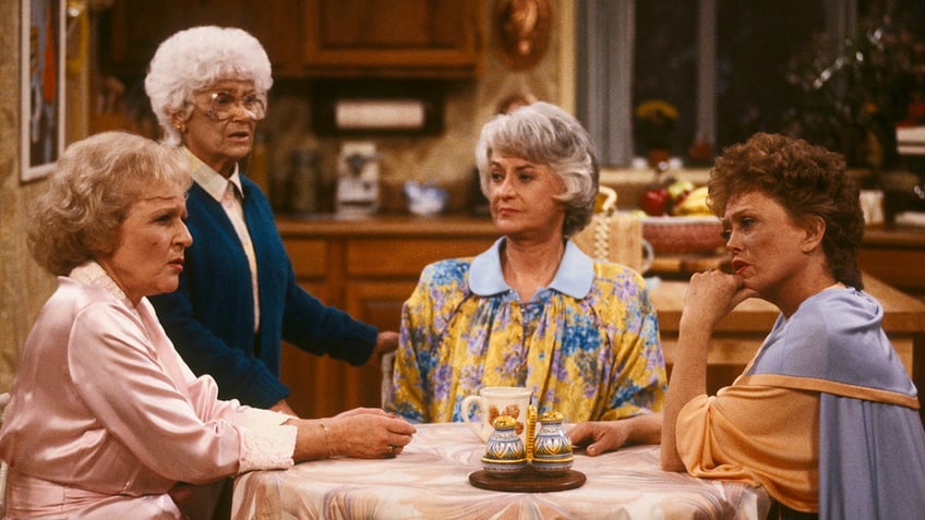 The cast of 'Golden Girls' sits around a table but Estelle Getty (Sophia) stands