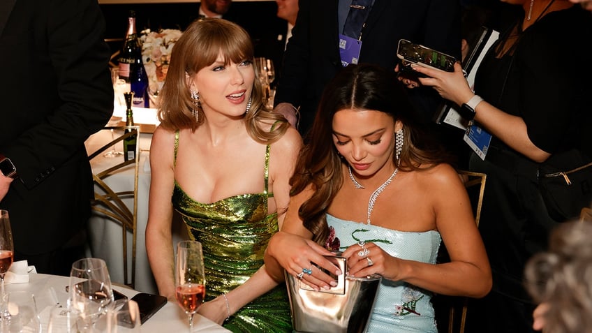 Taylor Swift and Keleigh Teller sit at the Golden Globes table