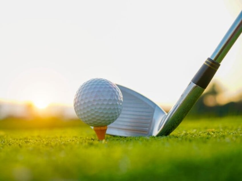 Golf clubs and golf balls on a green lawn in a beautiful golf course with morning sunshine