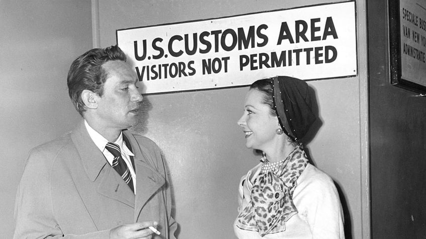 Peter Finch in a suit talking to a smiling Vivien Leigh