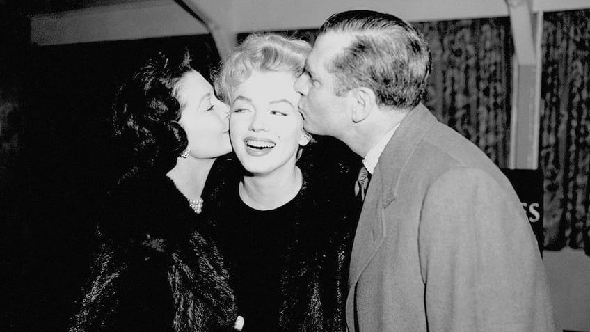 Vivien Leigh and Laurence Olivier giving Marilyn Monroe a kiss.