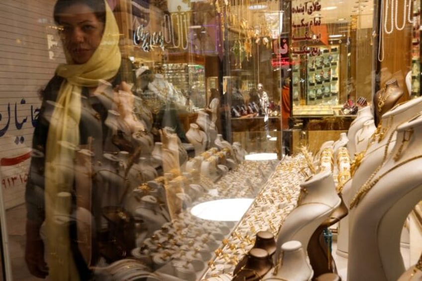 A woman walks past the display window of a gold jewelry shop in the old market of Yazd, in