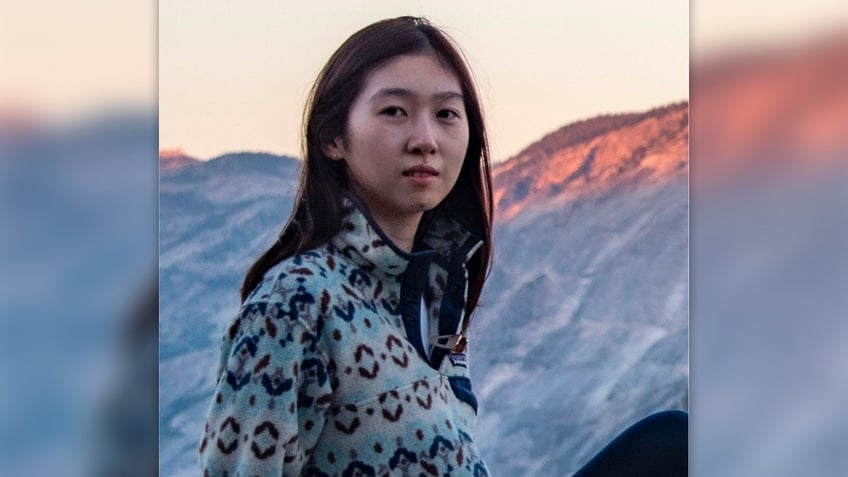 Xuanyi Yu stands in front of a mountain range at sunset