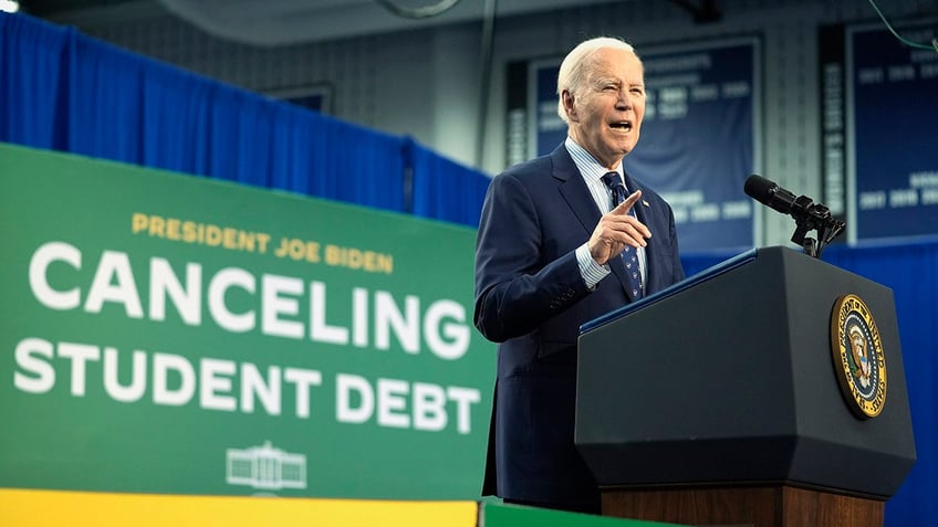 Biden points on stage in Madison during student debt handout event