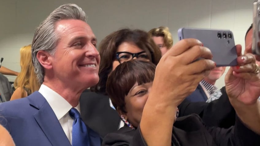 California Gov. Gavin Newsom poses for a selfie photo with supporters at the Democratic National Convention in Chicago on Aug. 19, 2024.