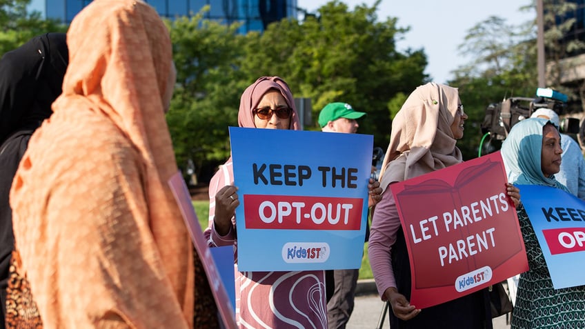 parents holding signs at outdoor protest rally