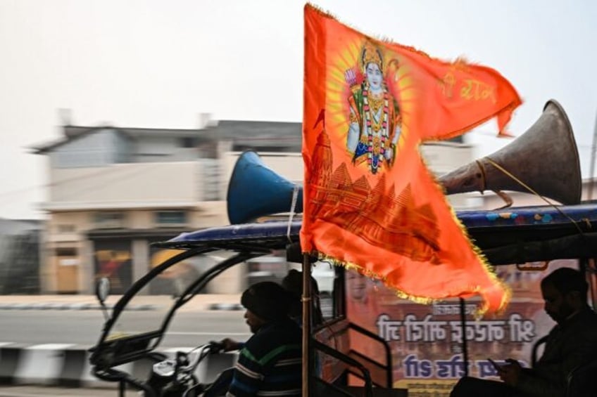 A flag depicting Hindu deity Ram is flown on an electric rickshaw as it rides along a street in Ayodhya