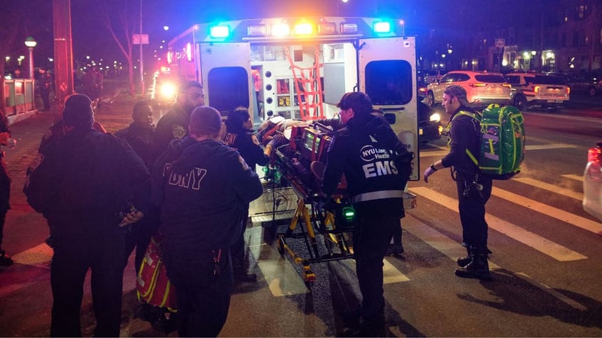 Medics and police place a shooting victim on a gurney into an ambulance