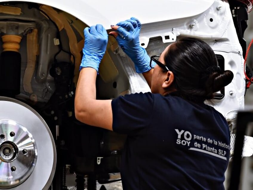 A BMW's employee is pictured working on a BMW car assembley process in a guided visit