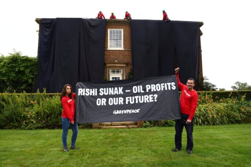 greenpeace demonstrators drape uk prime ministers house in black to protest oil expansion