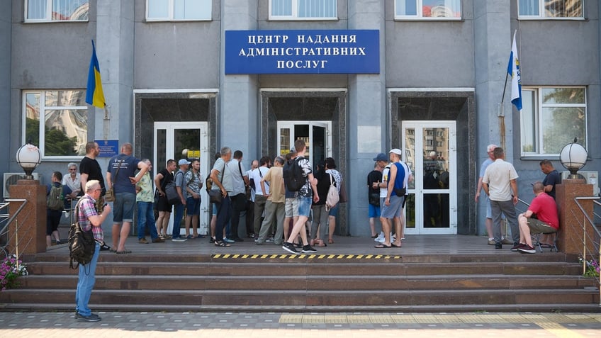 Ukrainian conscripts stand in line outside the Administrative Services Center to update their registration data in Kyiv, Ukraine.