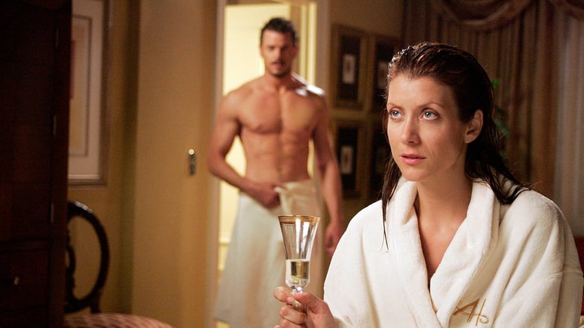 Eric Dane in nothing but a towel as Dr. Mark Sloan and Kate Walsh in a bathrobe holding a glass of champagne as Dr. Addison Montgomery