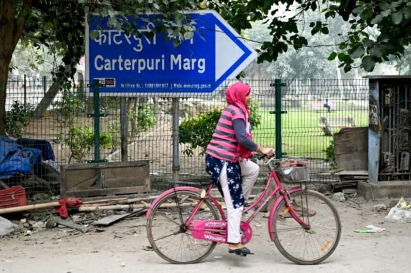 A cyclist rides past a sign pointing to Carterpuri, a village visited in 1978 by late US p