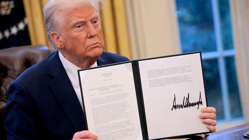 Trump holds up executive order in Oval Office