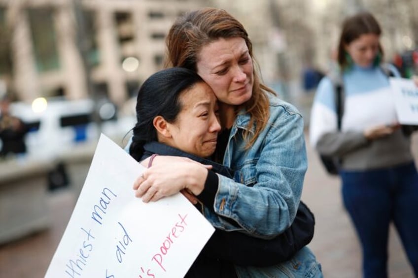 A woman cries as she embraces another outside the dismantled office of the United States A