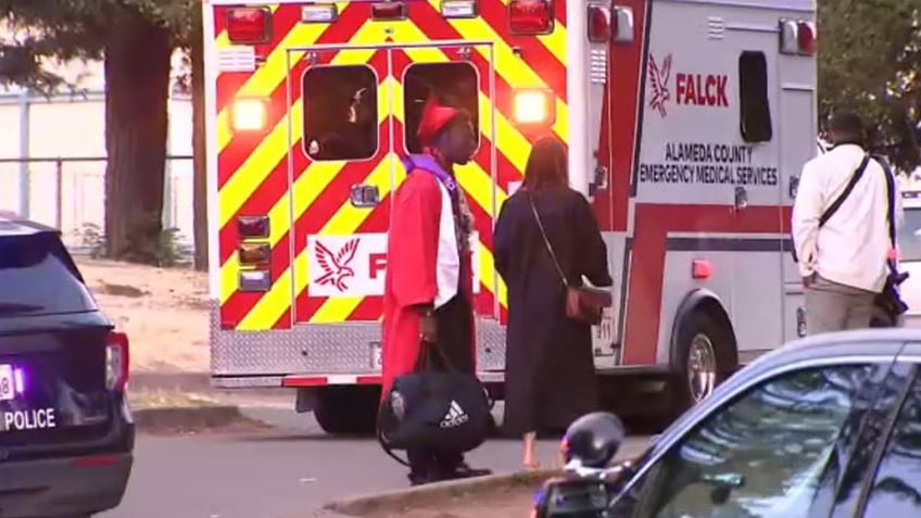 Graduates stand near departing ambulance