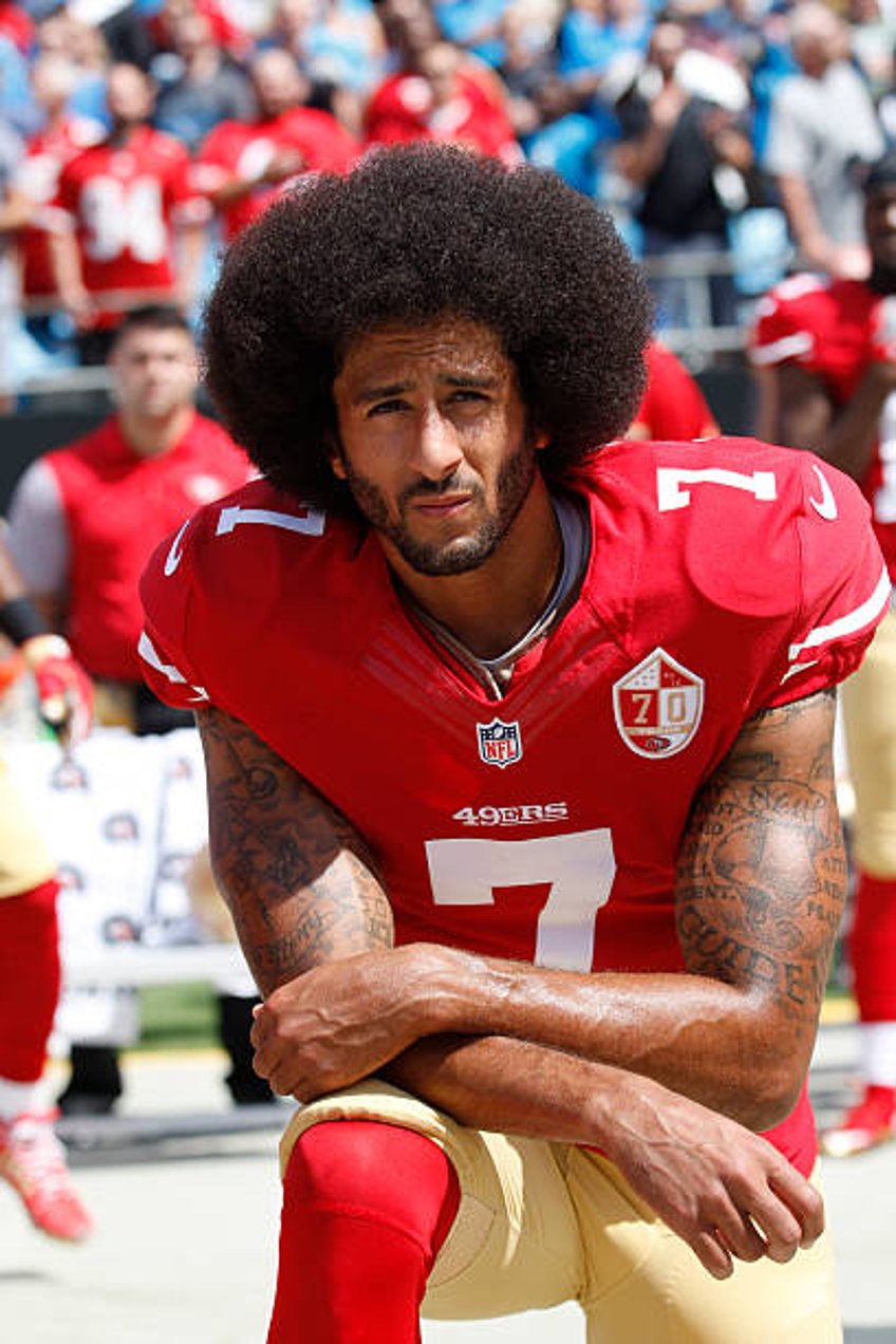 Colin Kaepernick of the San Francisco 49ers kneels during the anthem prior to the game against the Carolina Panthers at Bank of America Stadium on...