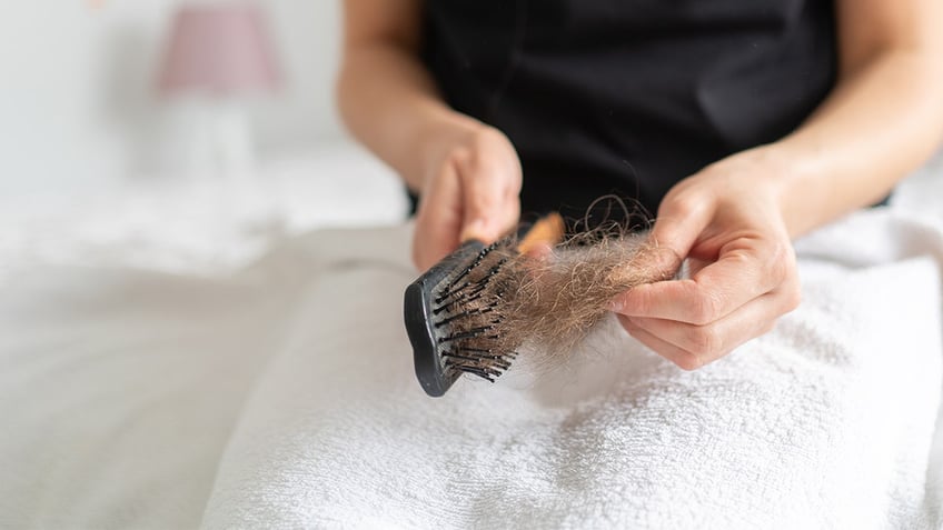 woman pulls hair out of brush
