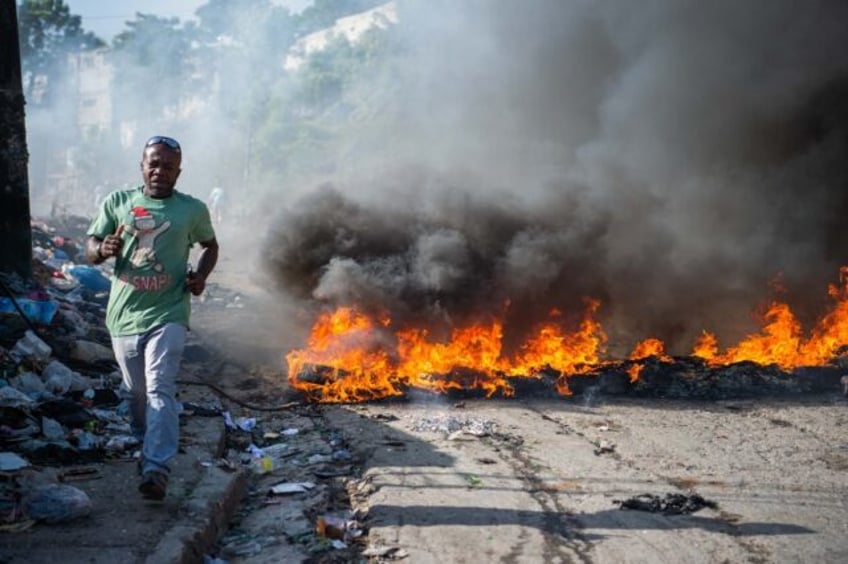 People walk past burning tires, during a demonstration against insecurity in Port-au-Princ