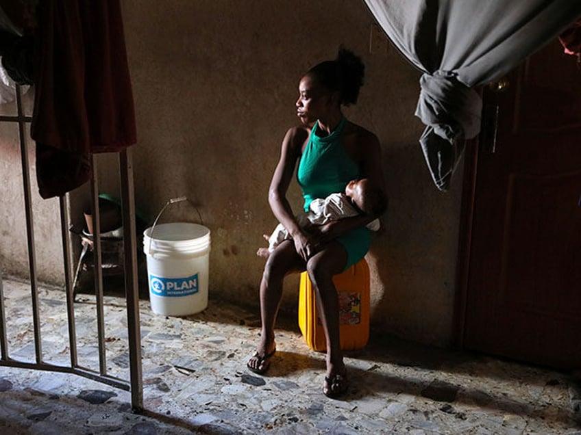 A displaced woman holds her baby inside a school that is now operating as a shelter for th