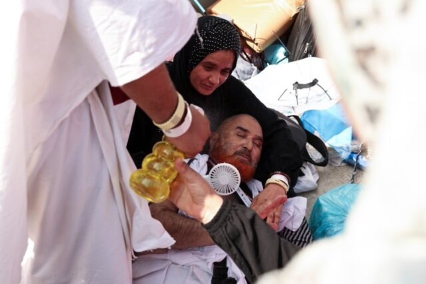 A pilgrim affected by scorching heat is helped by other Muslims in Mina, near Saudi Arabia