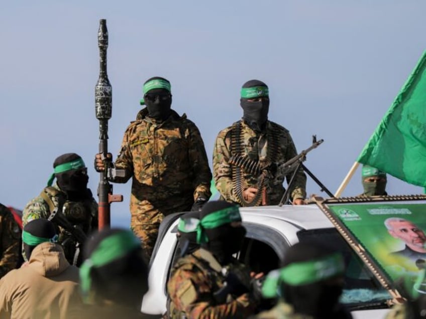 Palestinian militant group Hamas fighters secure an area before handing over an Israeli-Am