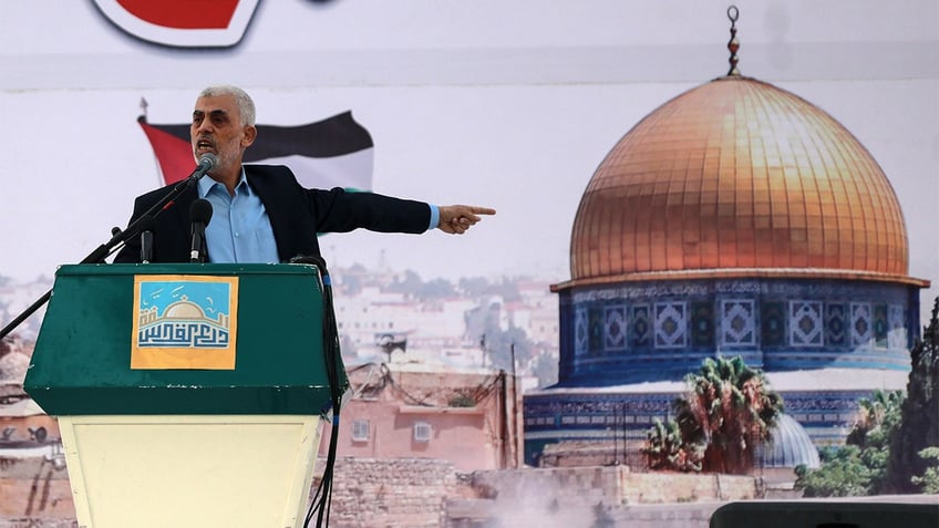 Yahya Sinwar speaks on stage while pointing.