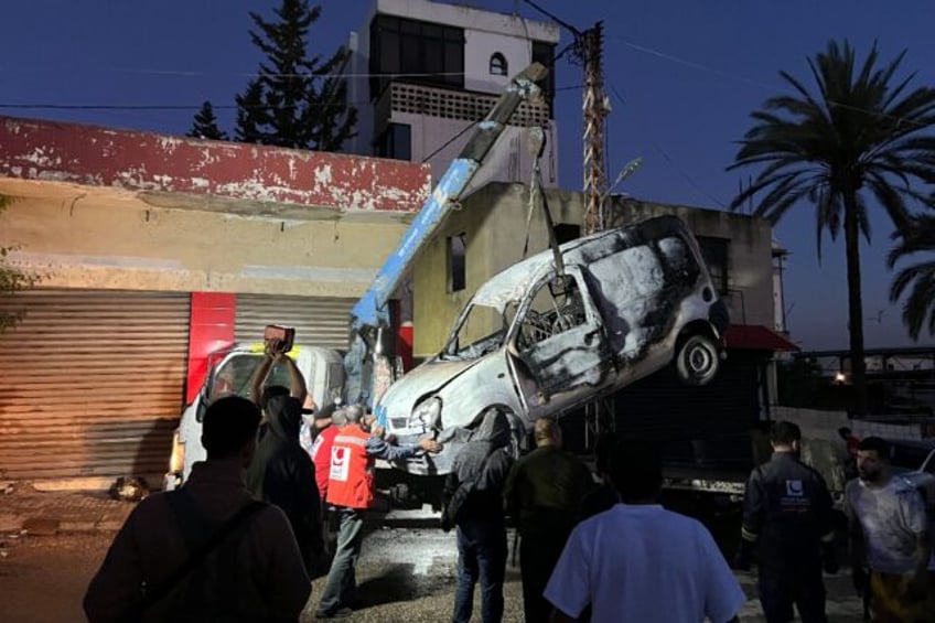 Lebanese soldiers stand guard as a recovery crew removes the vehicle in which a Hamas comm