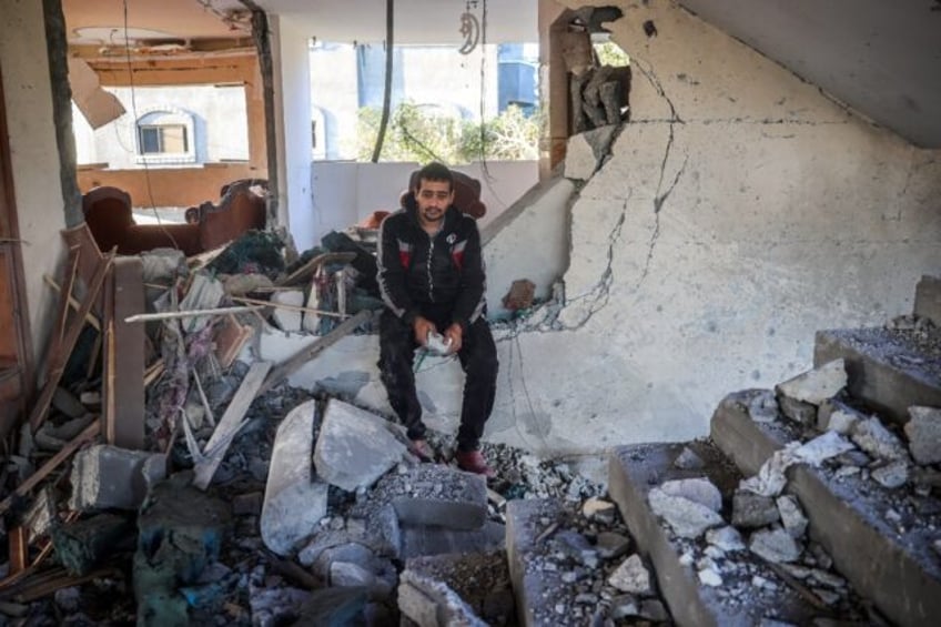 A man sits amid the rubble of a building following an Israeli strike on the central Gaza