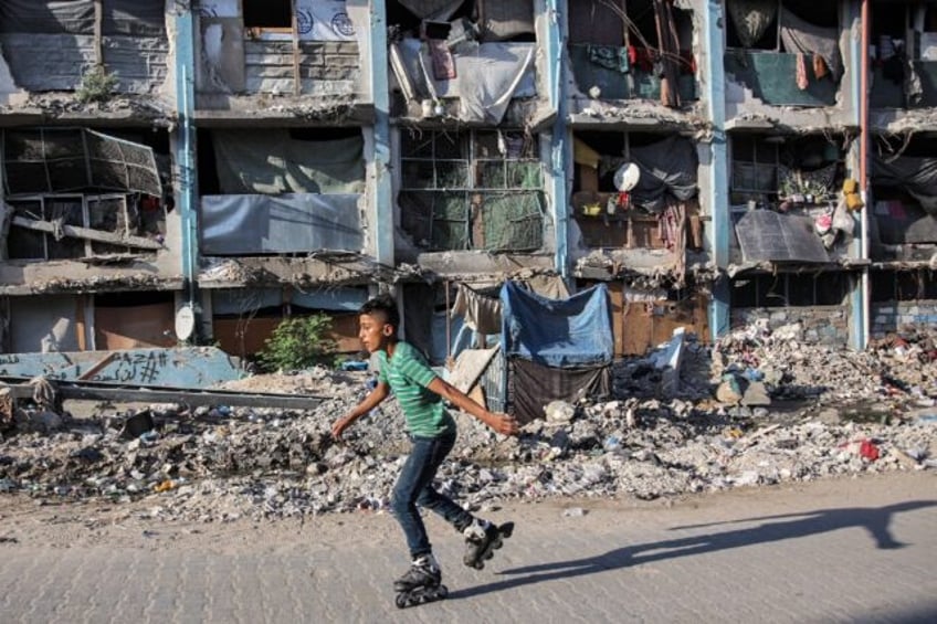 A boy roller-blades past a destroyed building at a camp sheltering people displaced by con