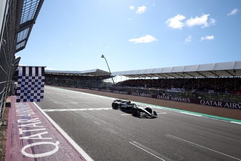 King of Silverstone: Lewis Hamilton crosses the finish line as Queen guitarist Brian May w