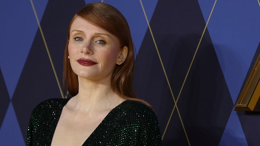 Bryce Dallas Howard in a sparkly dark green dress soft smiles on the carpet 