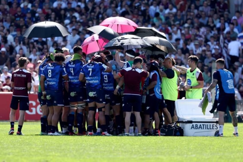 Bordeaux-Begles' players stand under umberallas during the Quins loss