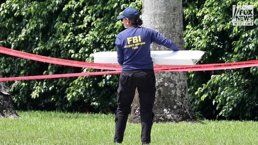 FBI investigators carry a box of evidence from the perimeter of Trump International Golf Club in West Palm Beach