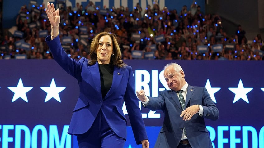 VP Kamala Harris waving with Gov. Tim Walz behind her to her left 