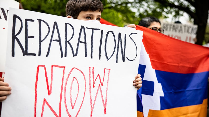 Boy holds reparations sign