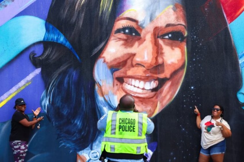 A Chicago police officer photographs people posing before a mural of US Vice President Kam