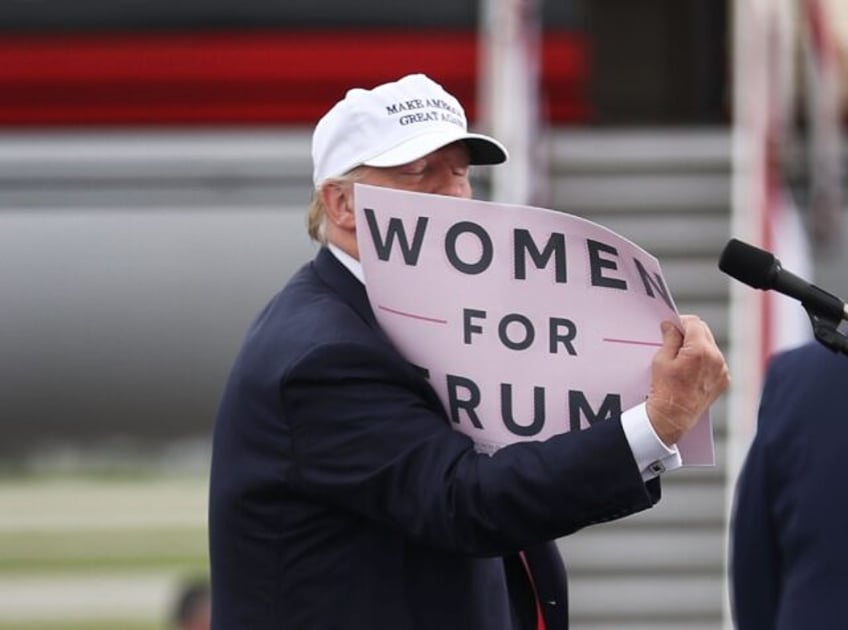 Donald Trump holds a sign that reads 'Women for Trump' during his 2016 presidential campai