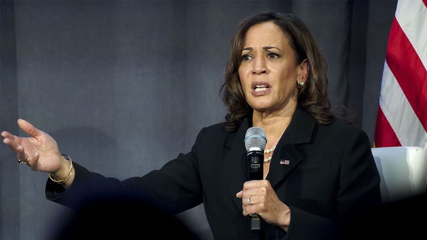 Kamala Harris dressed in all black holds mic during event