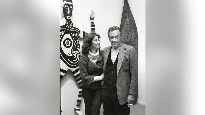 Stefanie Power on the arm of William Holden in front of African art.