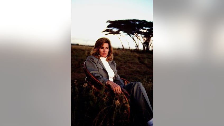 Stefanie Powers in a suit sitting in the outdoors of Africa.