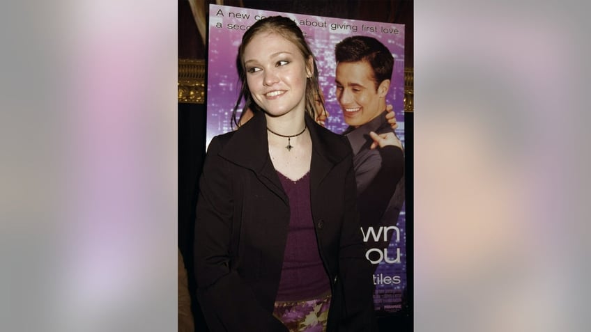 Julia Stiles posing in front of the "Down to You" poster