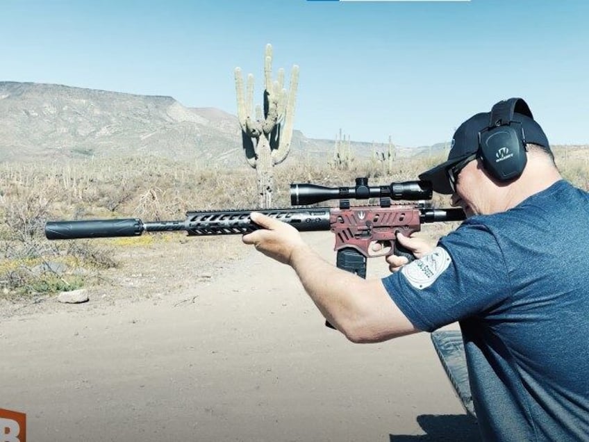 AWR Hawkins demonstrates shooting with a suppressor (screenshot AWR Hawkins/Breitbart News